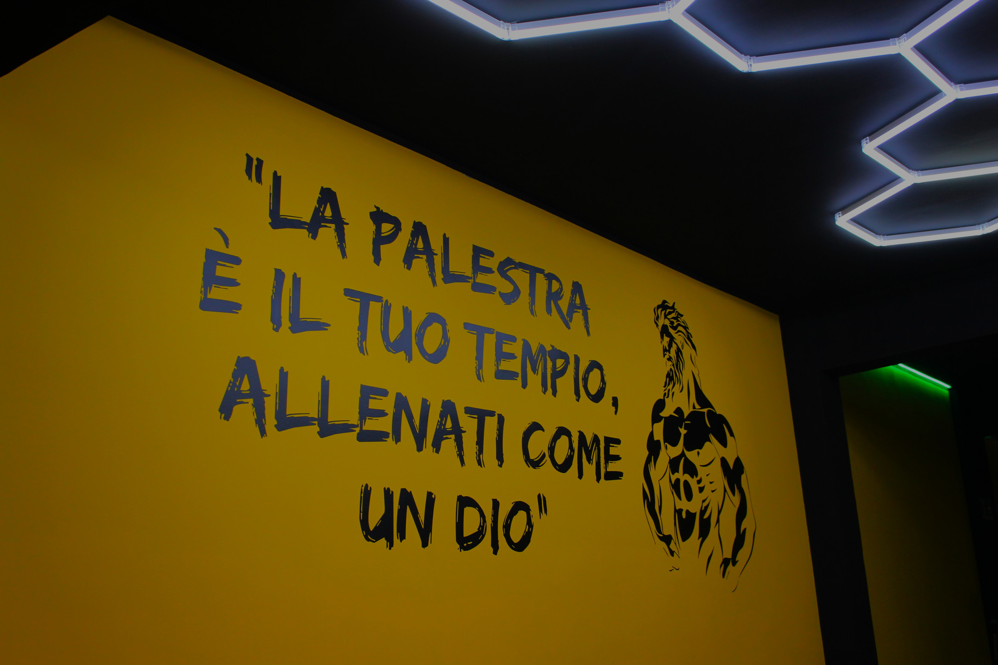 Murale motivazionale 'La palestra è il tuo tempio, allenati come un dio' nella palestra Chapo Fitness